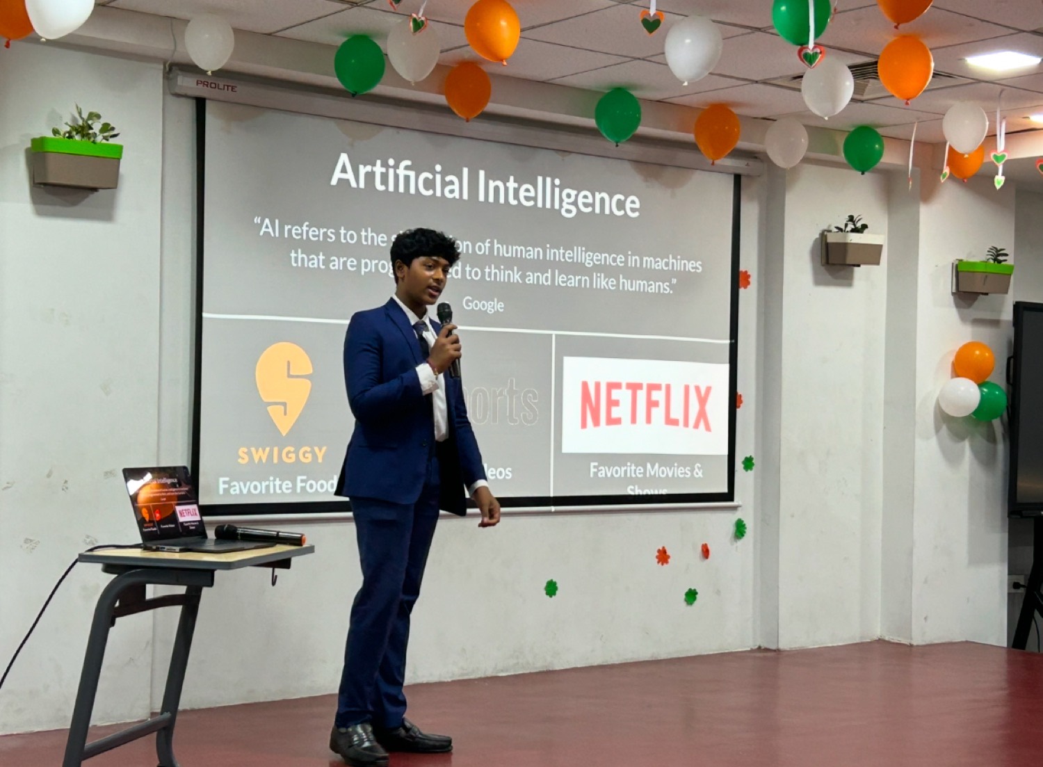 Shashank presenting the definition of artificial intelligence on a stage decorated with balloons